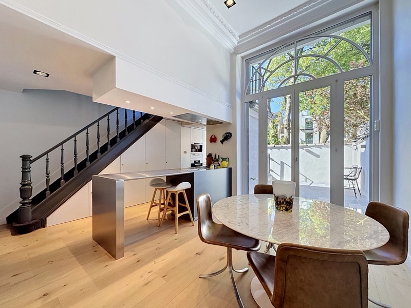 A double-height living space with a black staircase and arched glazing, in a Châtelain duplex